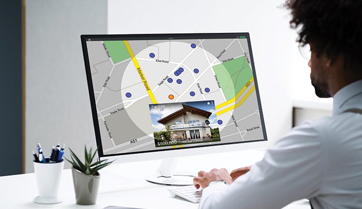 Male searching for homes on a computer that show a map with homes for sale marked with dots