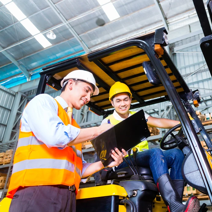 Blue collar workers with safety vests discussing documents on a clipboard.