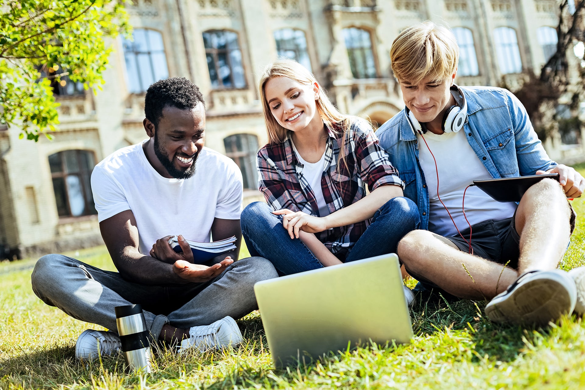 College students on lawn using laptop