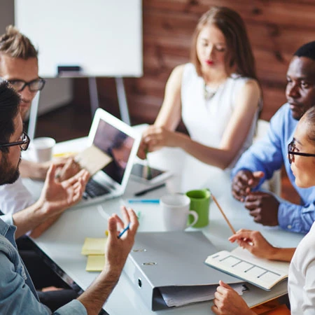 Business group sits at a table in engaged discussion.