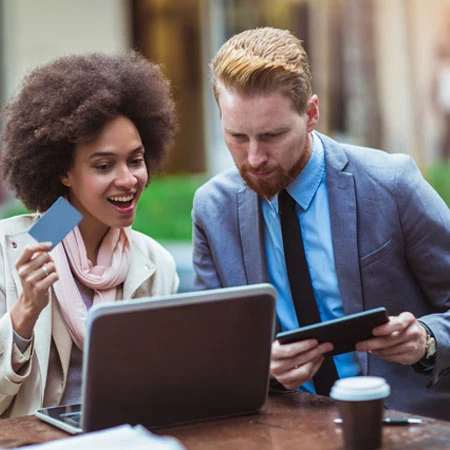 Two young professionals in business attire discuss financial card options.