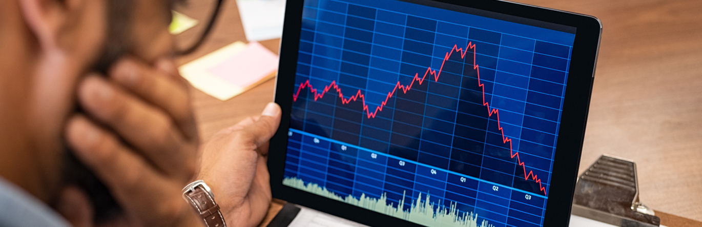 Gentleman with glasses looking at financial charts on a tablet.