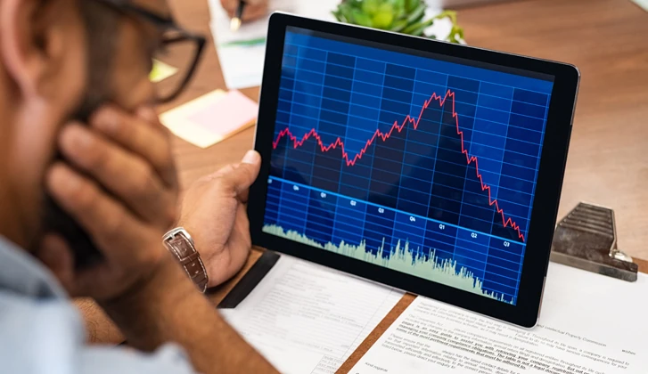 Gentleman with glasses looking at financial charts on a tablet.