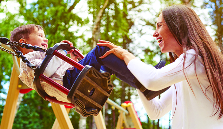 A young mother pushes her child on a swing.