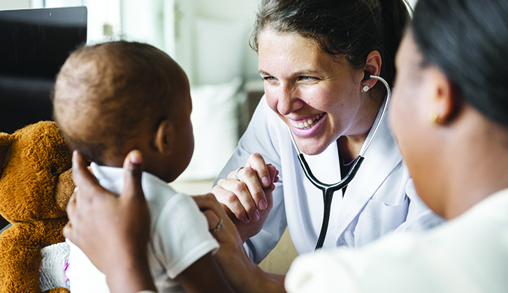 A doctor examines a baby with a stethoscope.