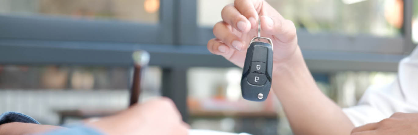 A hand stretches out holding a vehicle keyfob