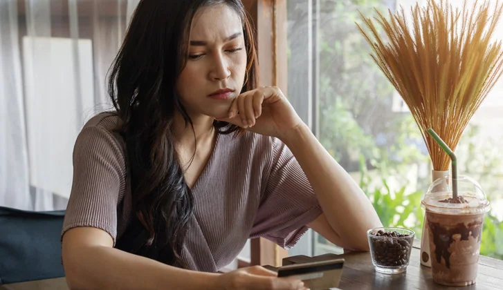 Woman thinking while looking at a credit card