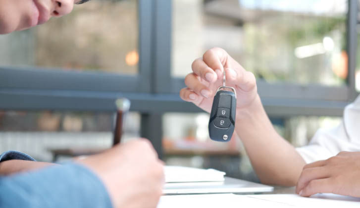 A hand stretches out holding a vehicle keyfob