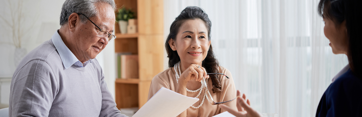 Elderly couple reviewing documents while an estate official explains.
