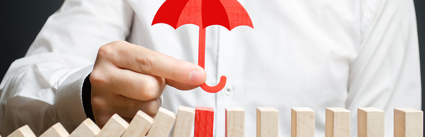 Gentleman holds small red wooden umbrella over row of wooden blocks. The one directly under the umbrella is also painted red.