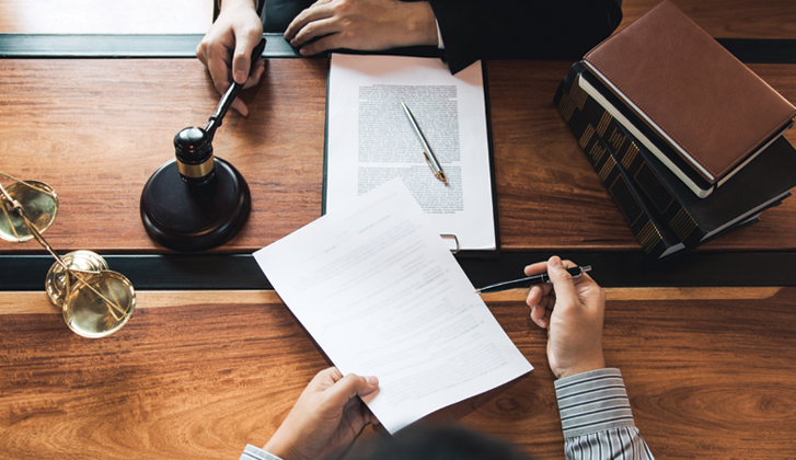 Fancy wooden desk top with legal documents and gold-trimmed supplies.