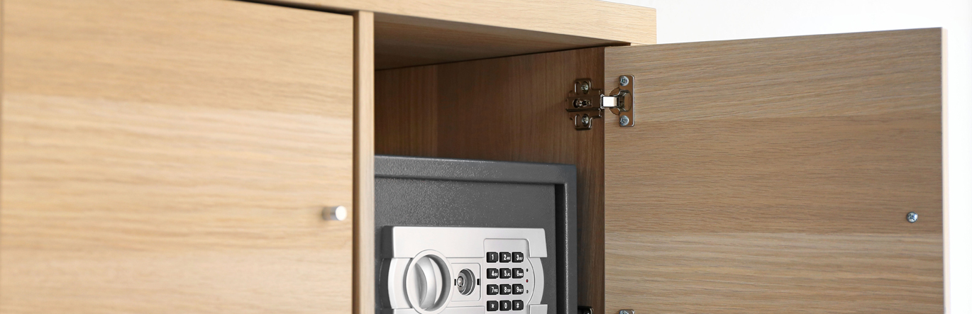 Locked safe with a number pad inside a wooden cabinet.