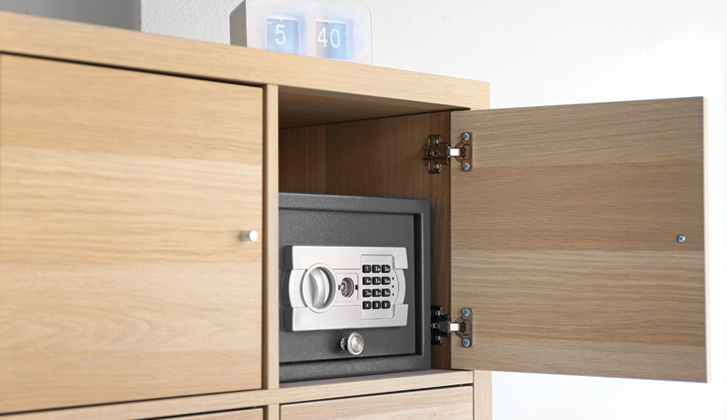 Locked safe with a number pad inside a wooden cabinet.