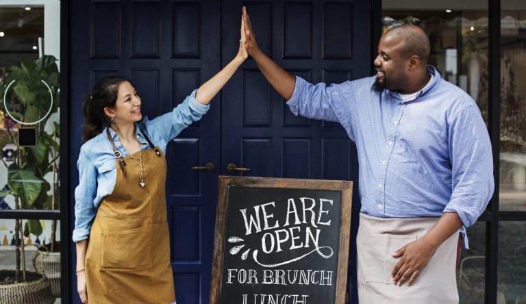 Female and Male business owners holding Open sign