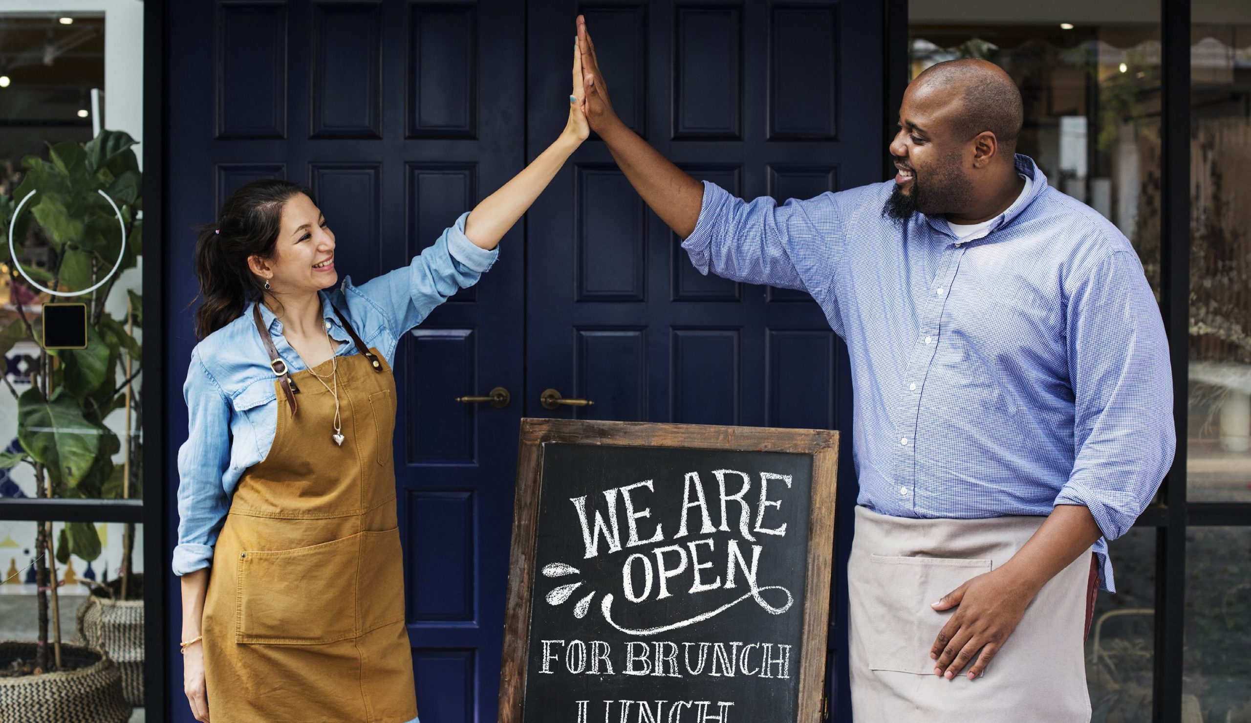 Female and Male business owners holding Open sign