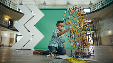 Young child works on building a puzzle in front of a green structure with the WesBanco Mark