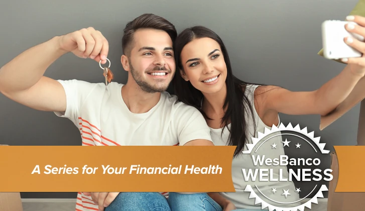 Happy couple holds up keys and takes a selfie in new house