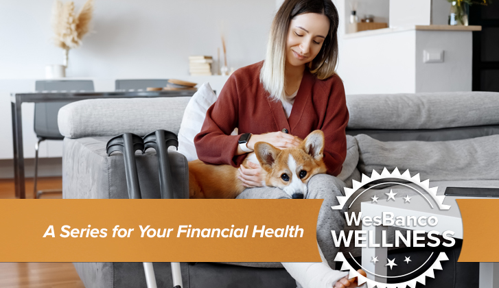 Woman in a cast sits on couch with her dog.