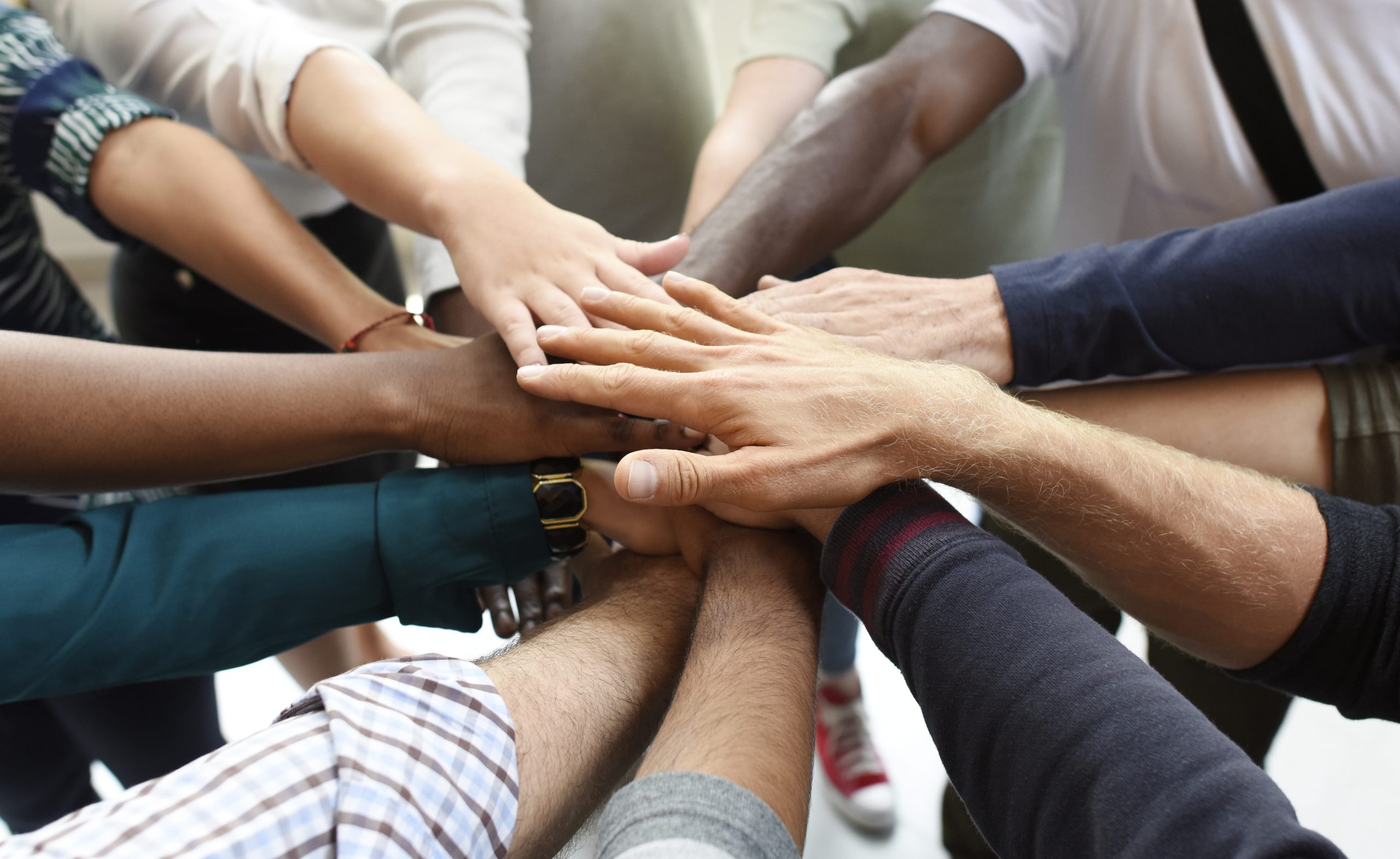 people standing in a circle with their hands in the middle