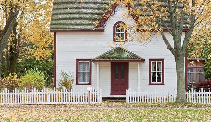 White house with red door and falling leaves