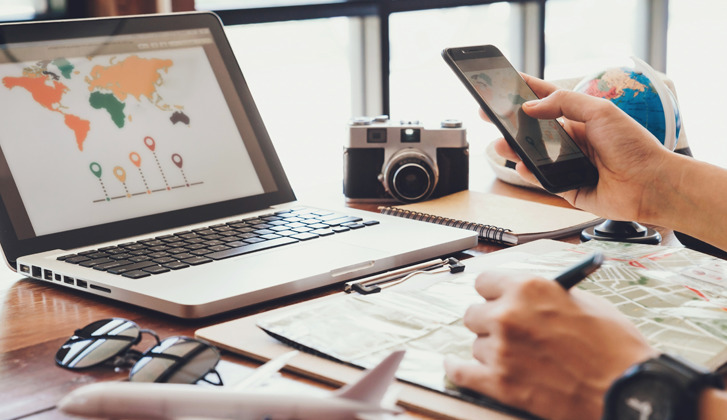 Person using laptop and cellphone to book a vacation