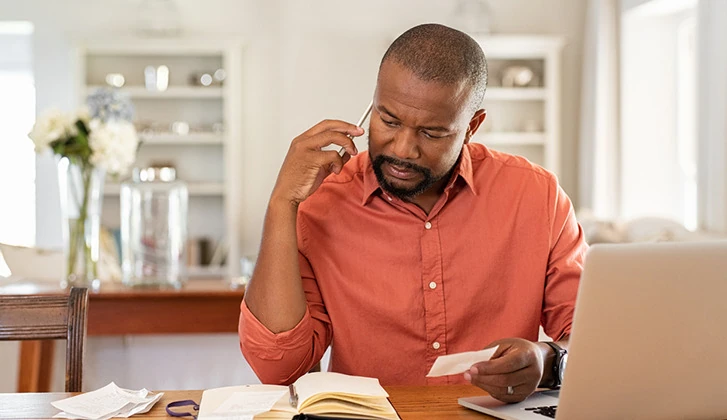 Man looking at statement and making phone call