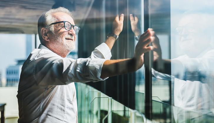 Man looking out office window on sunny day