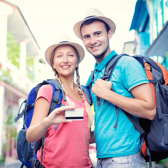 couple on a vacation abroad, holding up a credit card