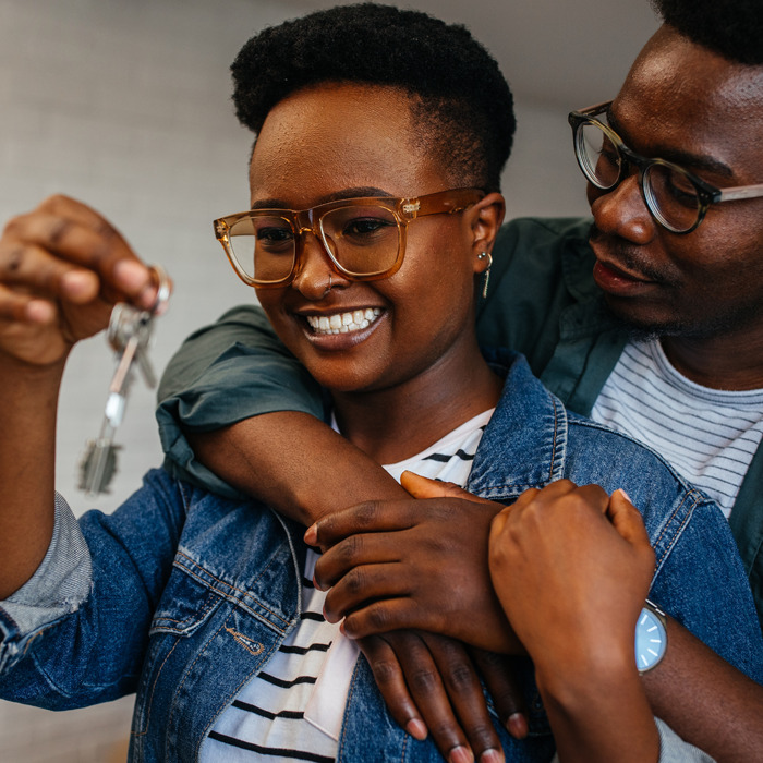 Couple holding up the keys to their new home, smiling.