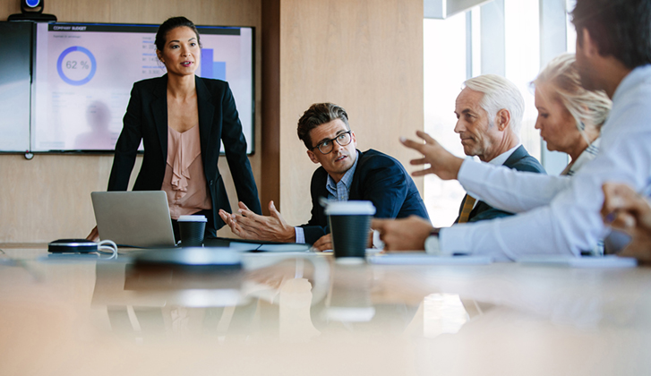 Woman overseeing discussion at business room table