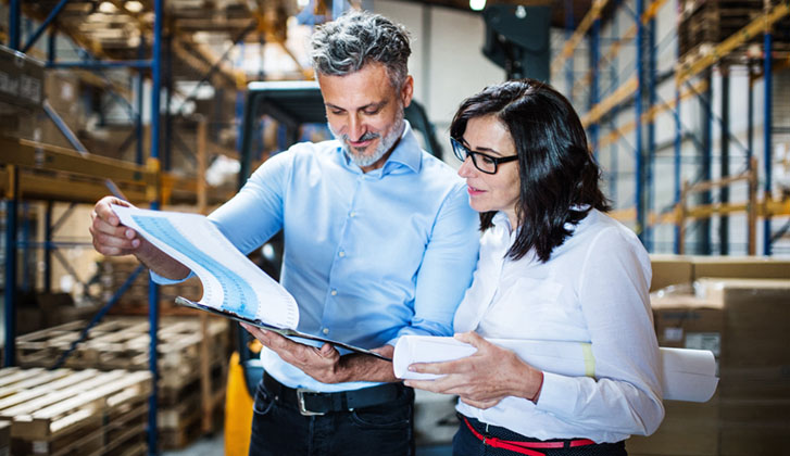 man and woman reviewing paperwork in warehouse