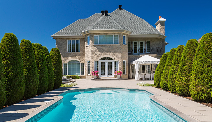 A white stone house with a swimming pool.