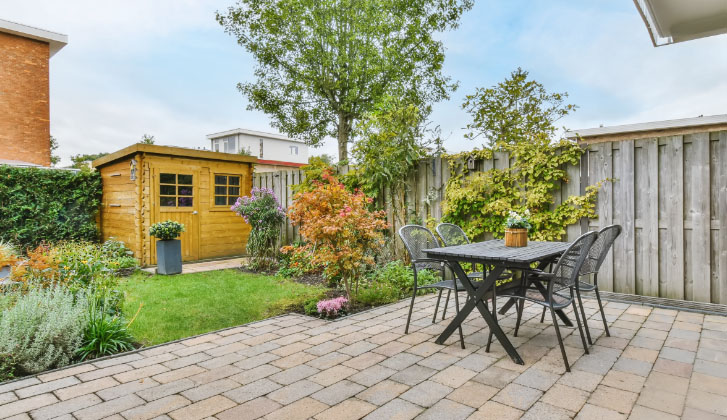 An backyard setting, with a deck table and garden shed in the background.