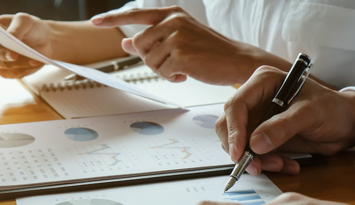 Two business people reviewing documents on a desk side by side
