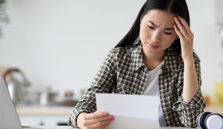 Young Asian woman frowning while looking over documents.