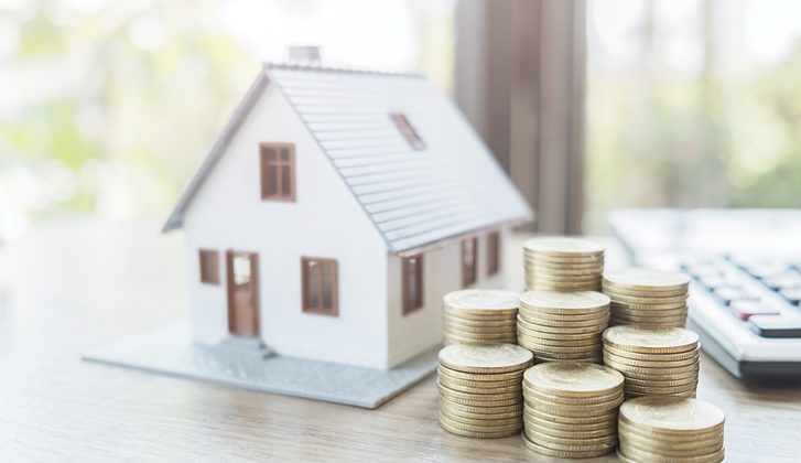 Model house and a stack of gold dollar coins.