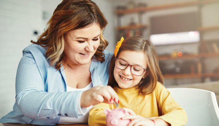 Mother and daughter place coins into a piggy bank.