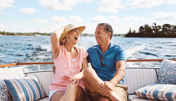 Couple in their 40s/50s laugh together while on a boat ride.