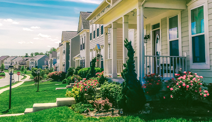 A neighborhood of single family homes, all in a row. The sky is clear, and the weather is sunny.