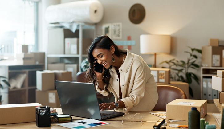 Phone call, small business or happy woman with laptop for ecommerce communication in office. Typing, smile or Indian manager listening in conversation or speaking of news, feedback or networking.