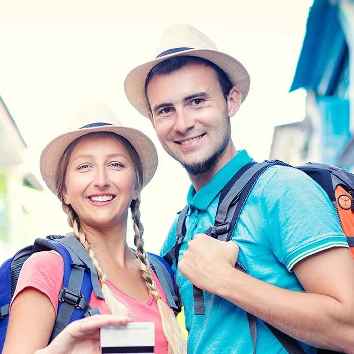 Smiling tourist couple posing with their credit card