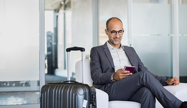 man in business suit sitting in an airport next to his luggage