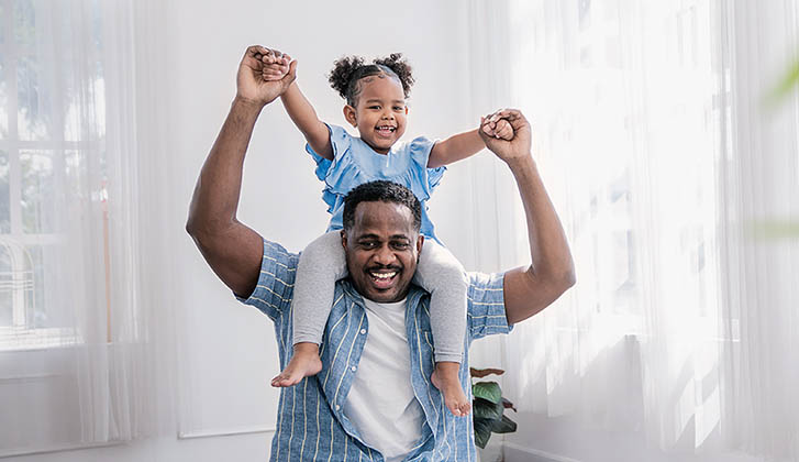 Happy African American father daughter playing at home living room.