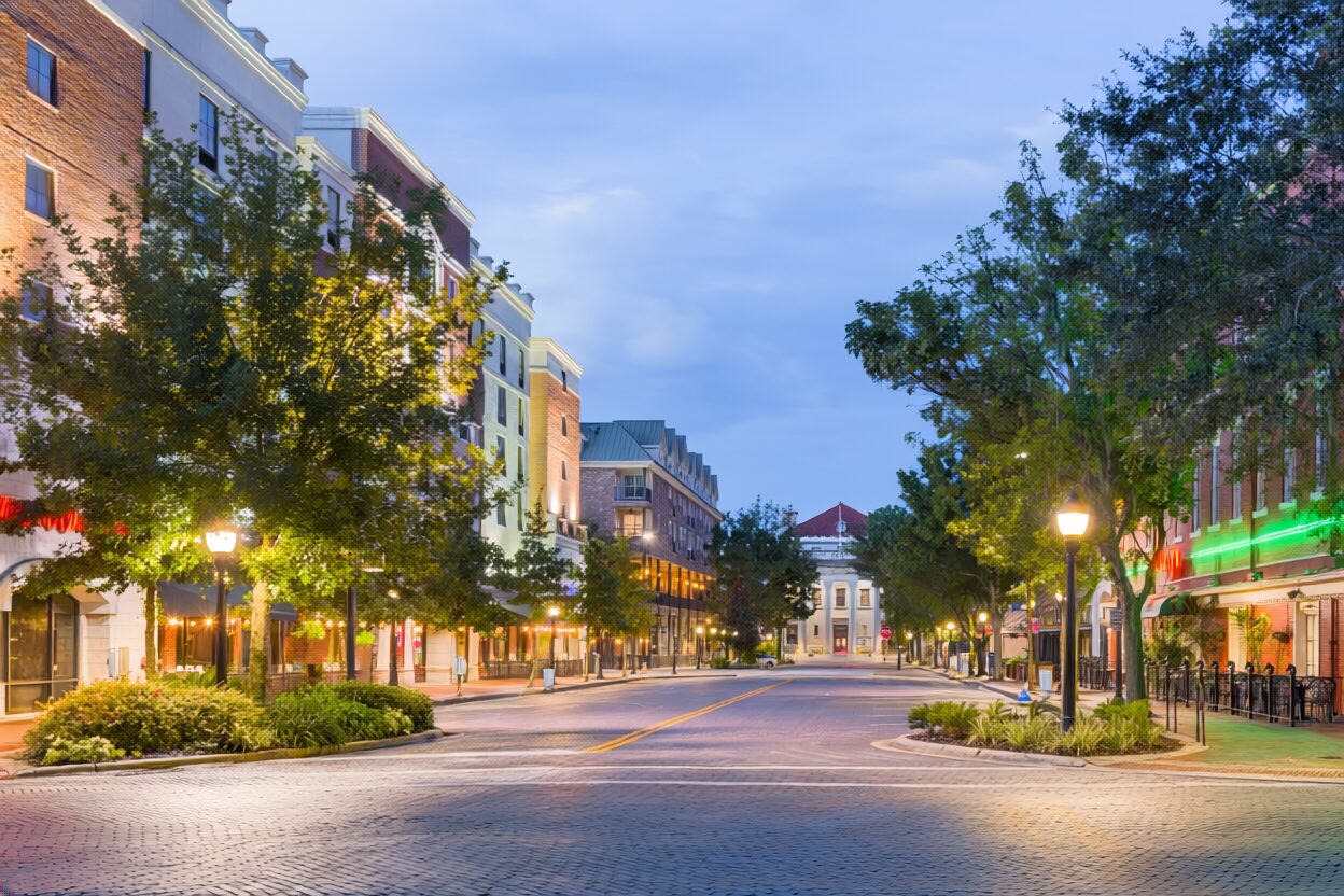 An american hometown street in the evening time lush with greenery, lit streetlamps and clean walkways